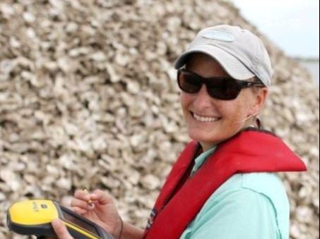 Haille Leija with a life jacket holding an oyster