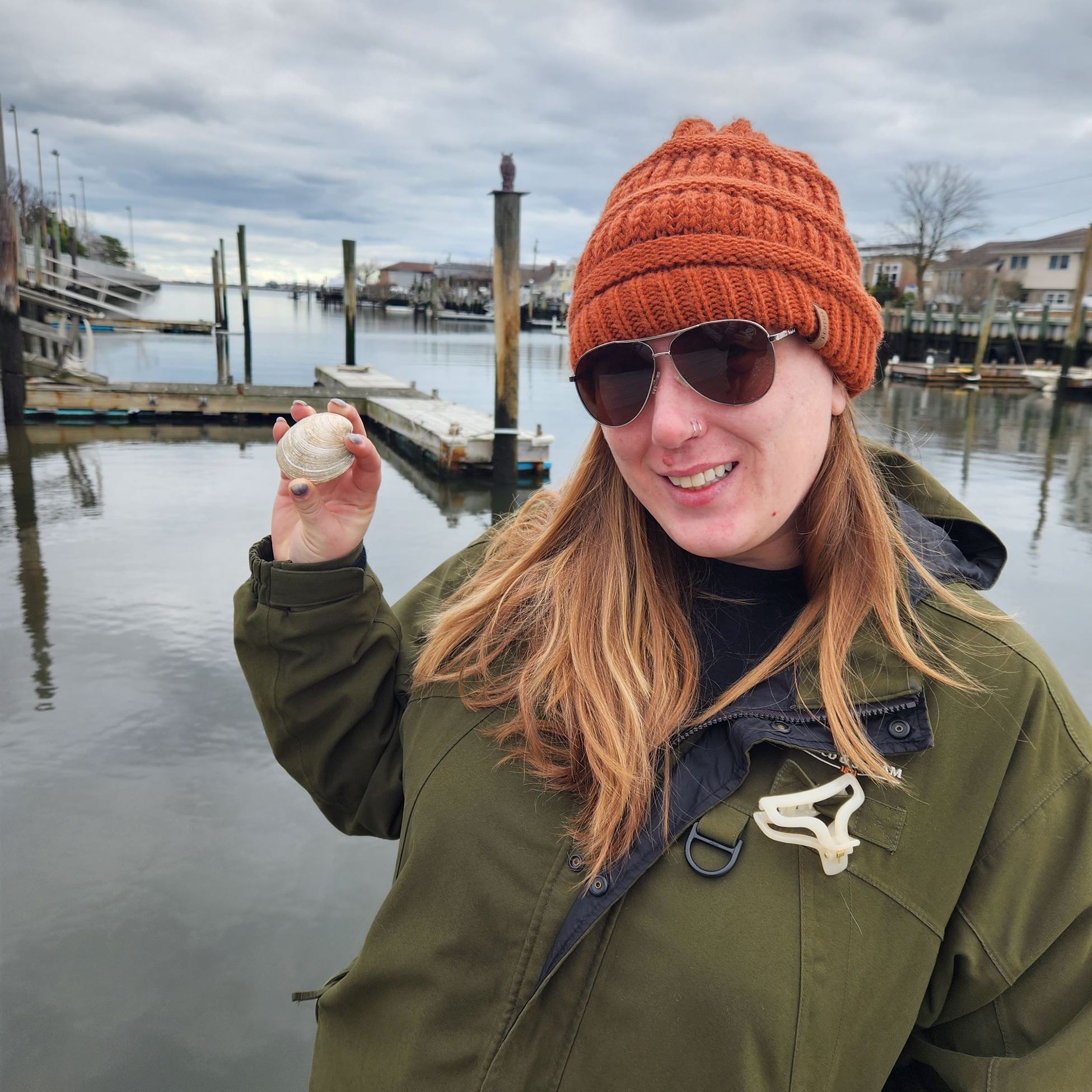 A young lady in an orange beanie holding a mussel shell